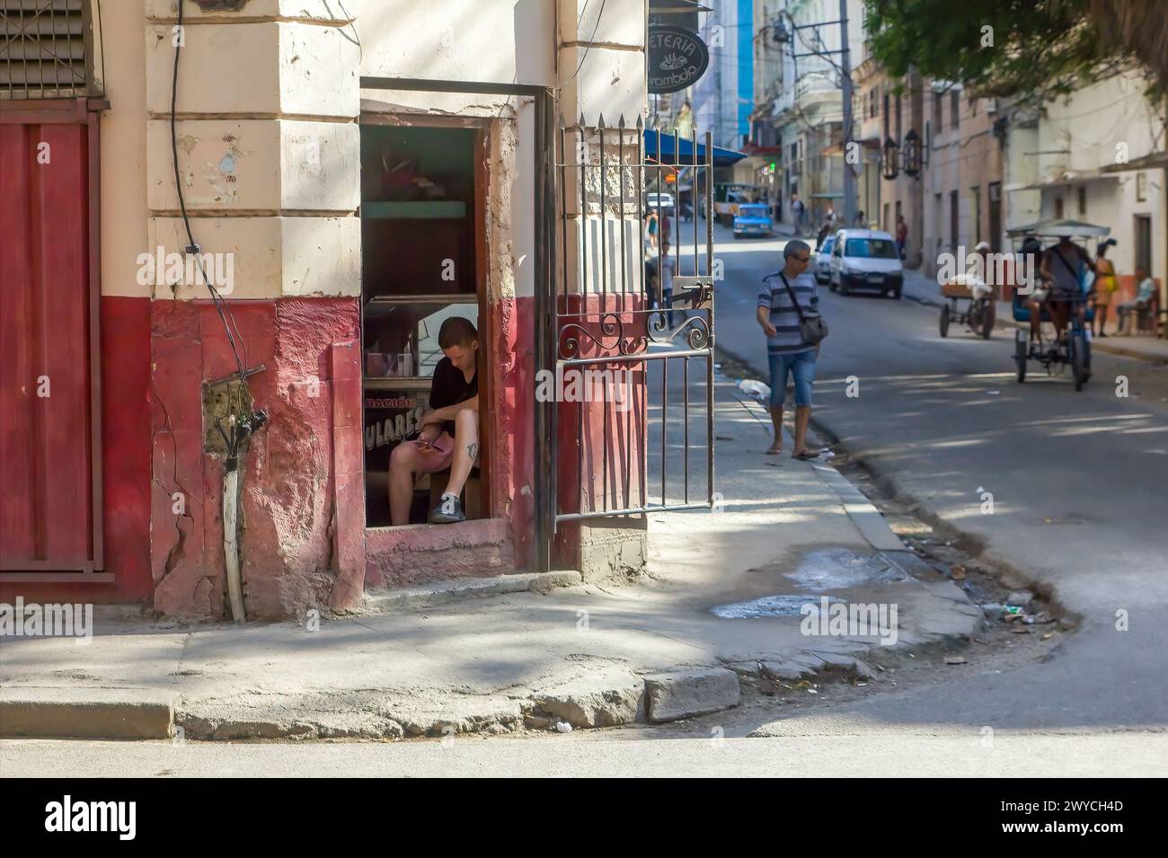 Man sitting while working, broken sidewalk in Havana, Cuba Stock Photo