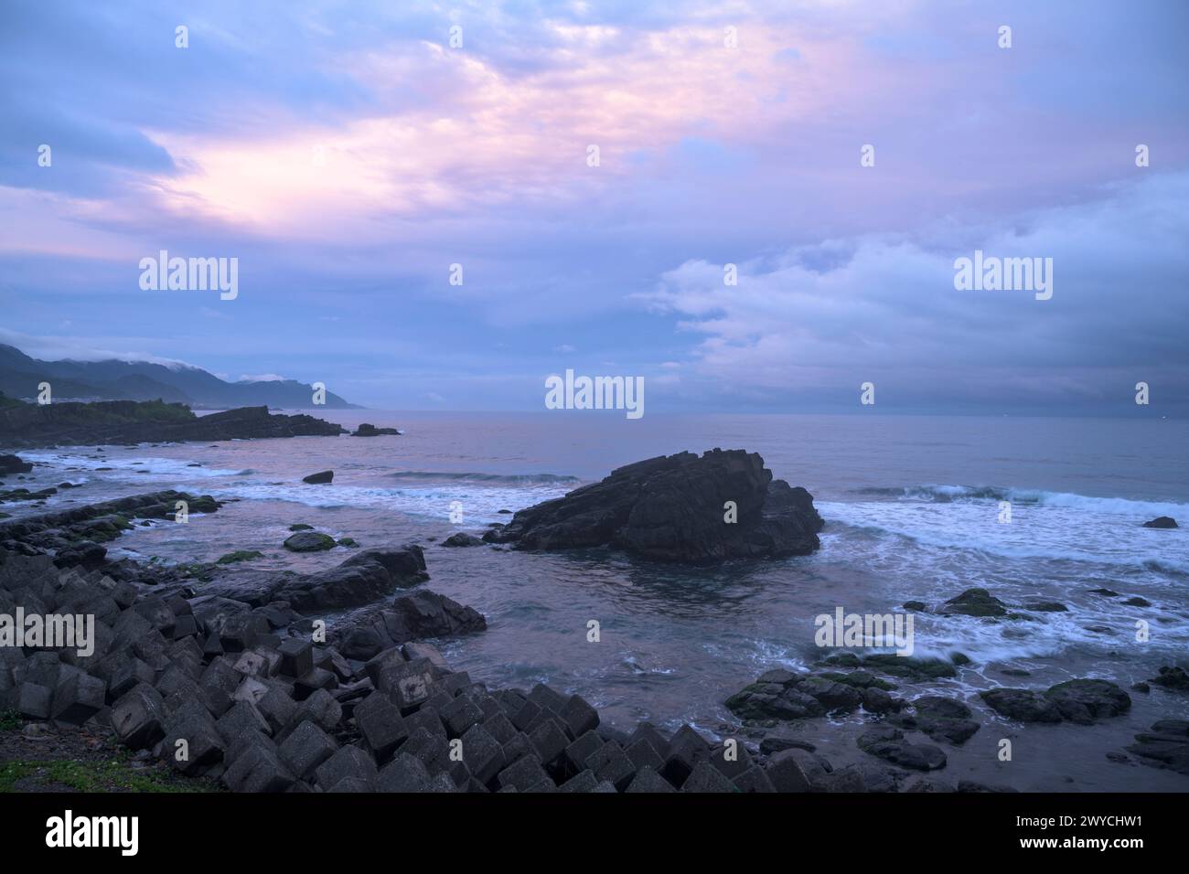 A panoramic view of a serene seascape with rocky formations at sunset Stock Photo