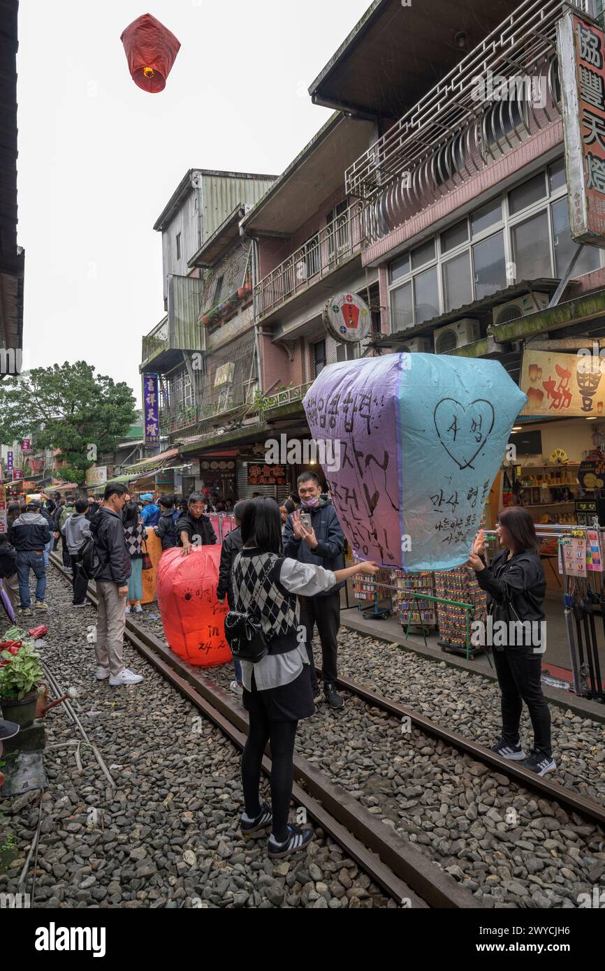 Tourists and onlookers participate in the release of lanterns to make wishes for the new year on the train tracks in Shifen Stock Photo