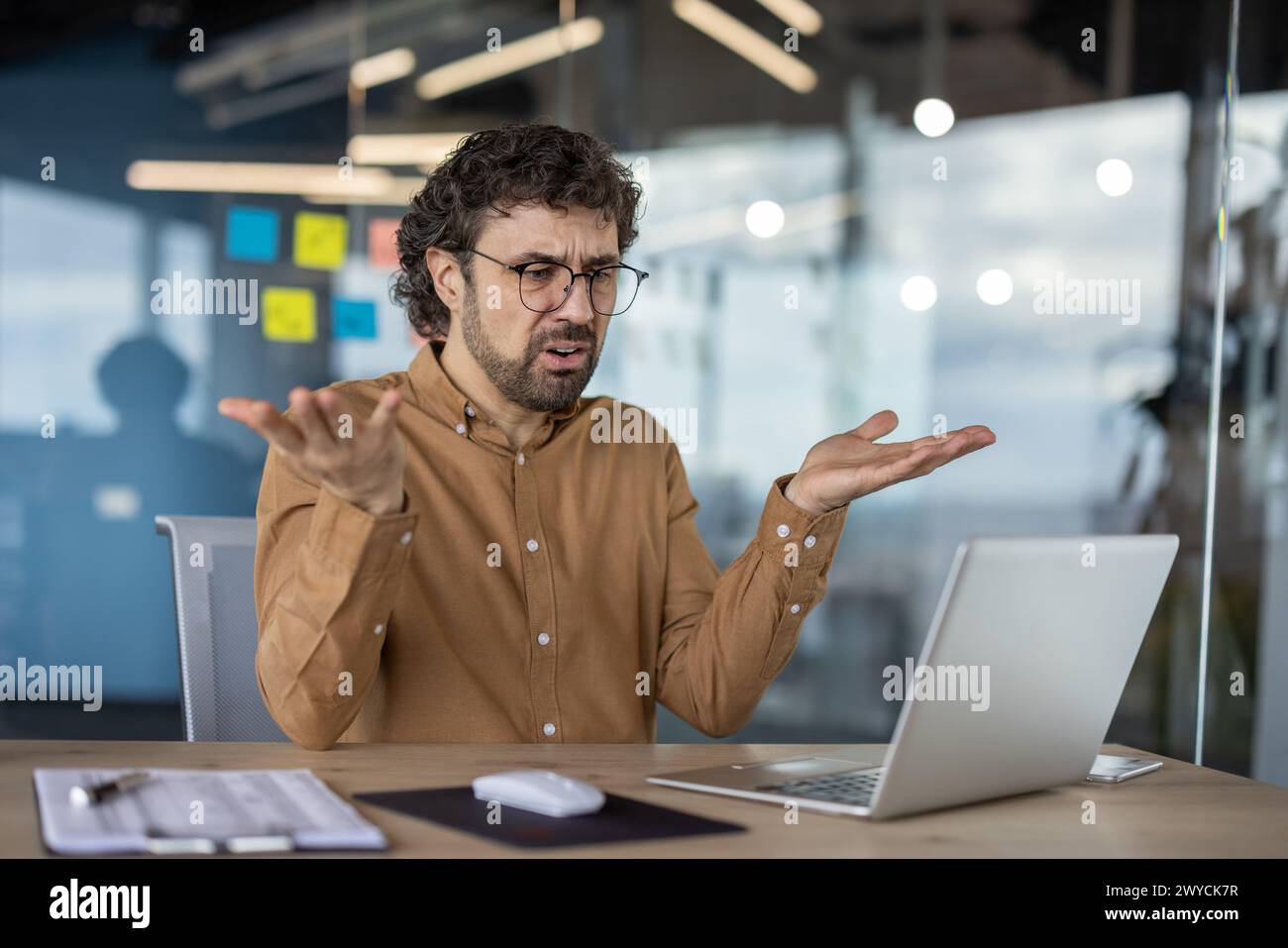An adult male in a casual shirt expresses confusion while using a ...