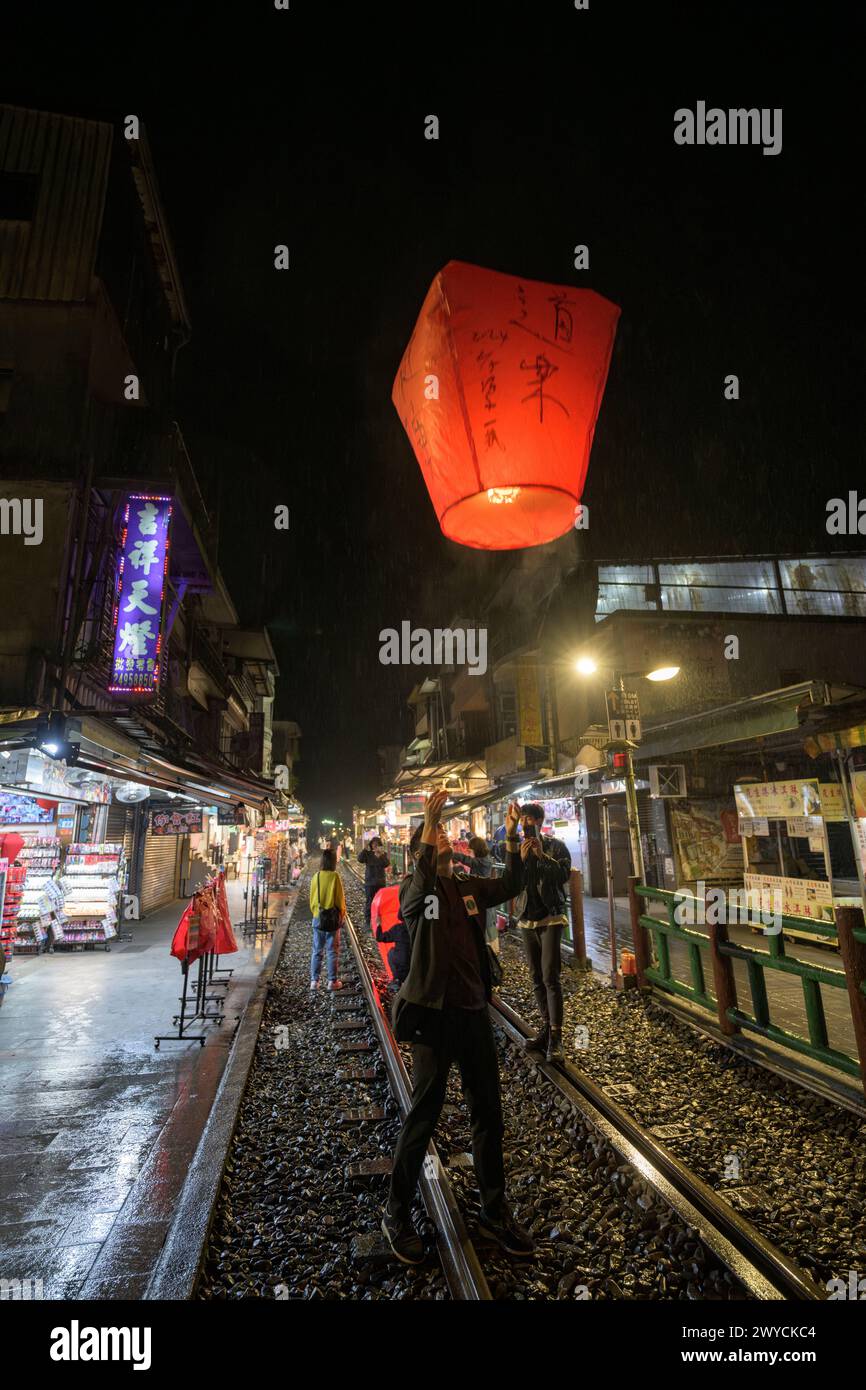 Tourists and onlookers participate in the nightly release of lanterns to make wishes for the new year on the train tracks in Shifen Stock Photo