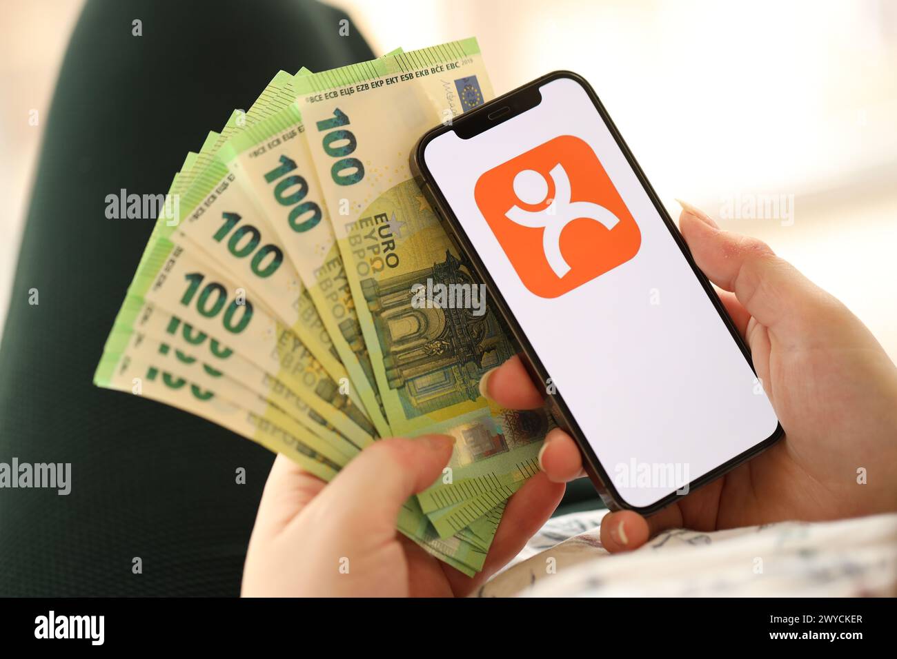KYIV, UKRAINE - APRIL 1, 2024 Dianping platform icon on smartphone screen and money in female hand. iPhone display with app logo and hundred euro bills in girls hands close up Stock Photo