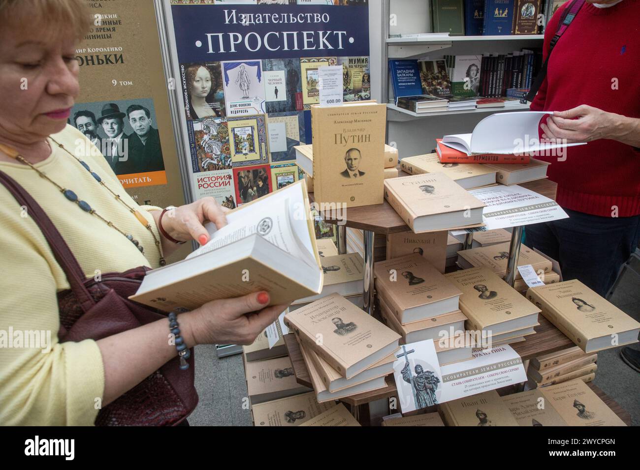 Moscow, Russia. 5th of April, 2024. A woman pages through a copy of Vladimir Putin. From the 21st Century Chronicles by Alexander Myasnkov on display during the 2024 non/fictioNvesna book fair at Gostiny Dvor in Moscow, Russia Stock Photo