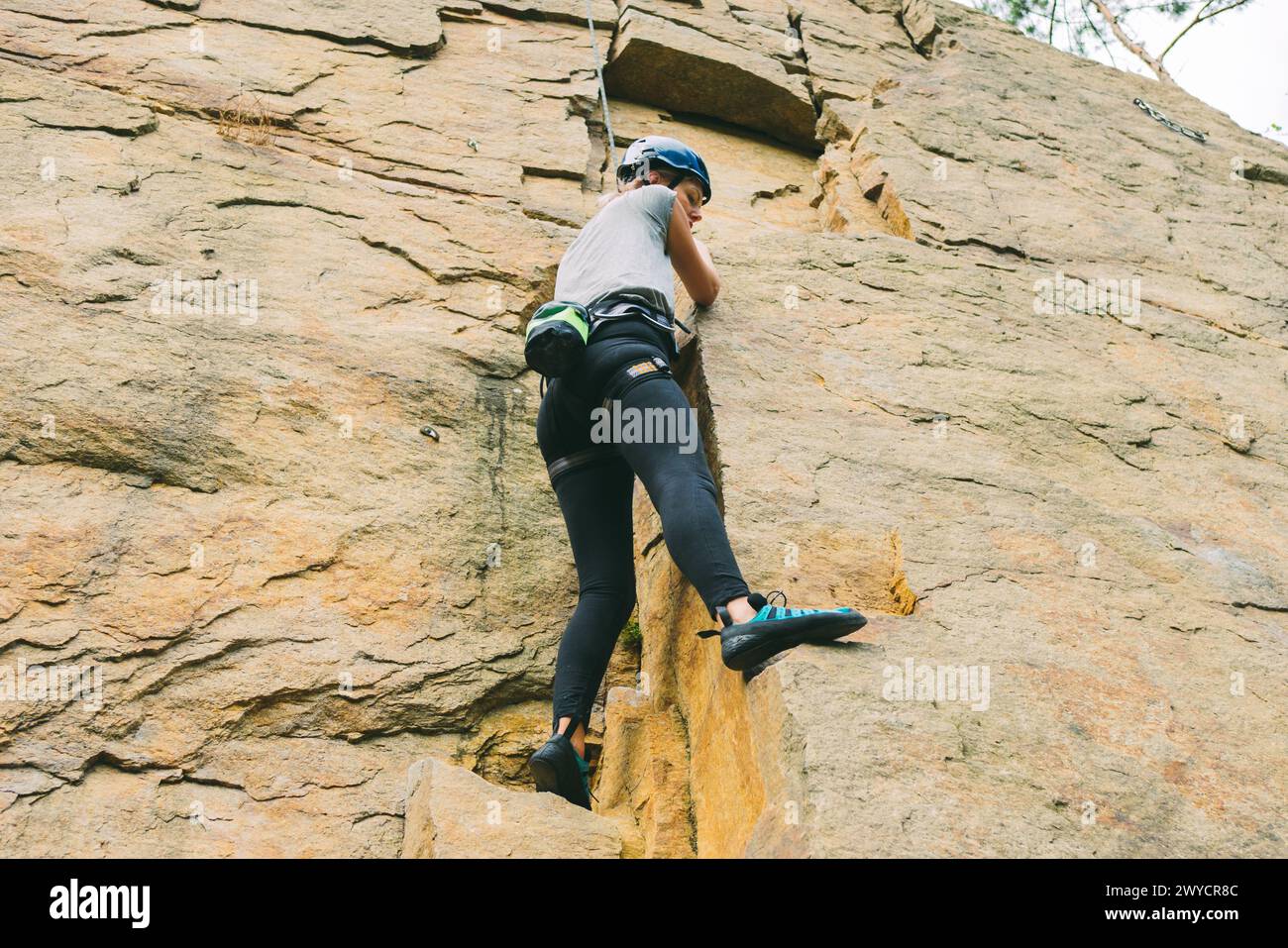 Young athletic woman in equipment doing rock climbing outdoors ...