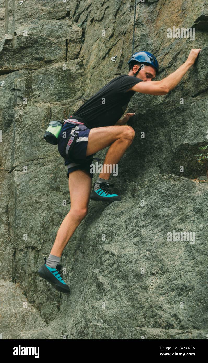 Young man in equipment doing rock climbing outdoors. Training area for outdoor activities. Extreme sport. Stock Photo