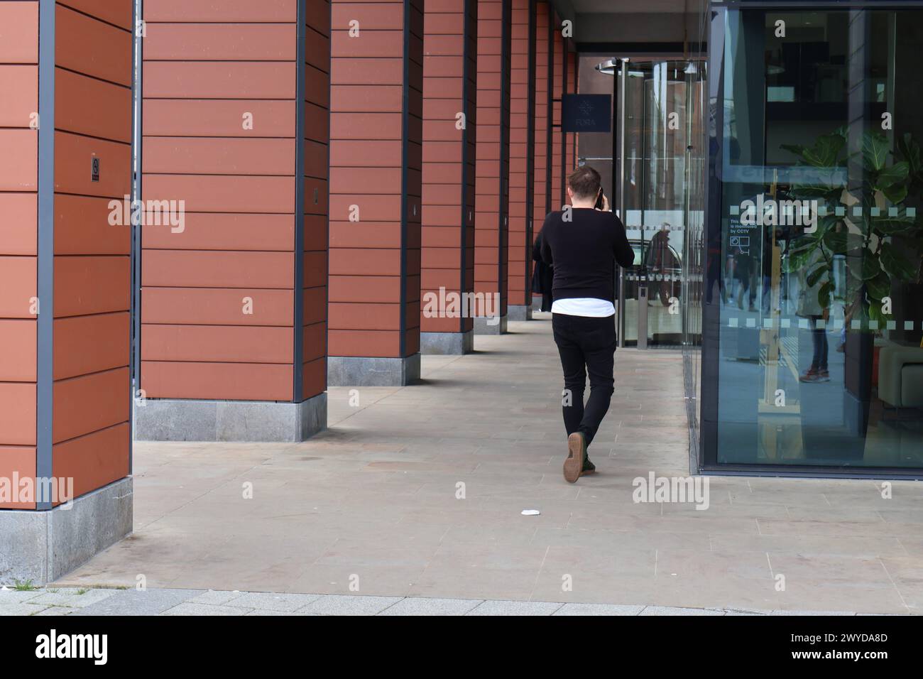 Man walking away outside Thames Tower in Reading Berkshire while talking on the phone on Friday 5th April 2024. Charles Dye / Alamy Live News Stock Photo
