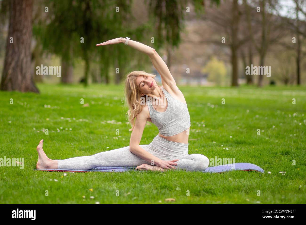 Woman doing side stretch in yoga pose outdoors. Stock Photo