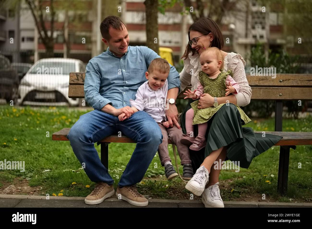 Family with two children sitting on a bench in the park Stock Photo