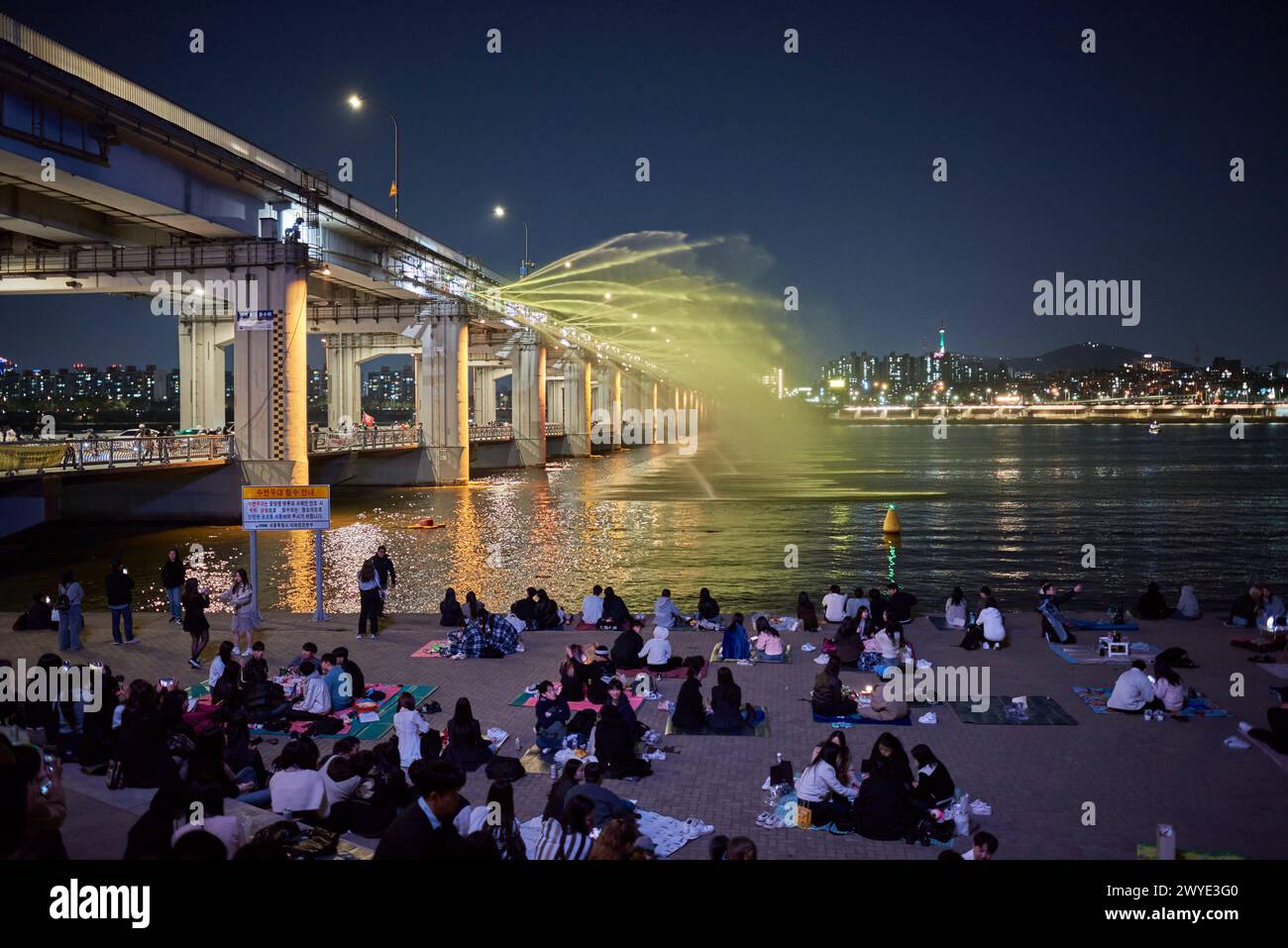 People watch colorful Banpo Bridge Moonlight Rainbow Fountain in Seoul, South Korea on 05 April 2024 Stock Photo