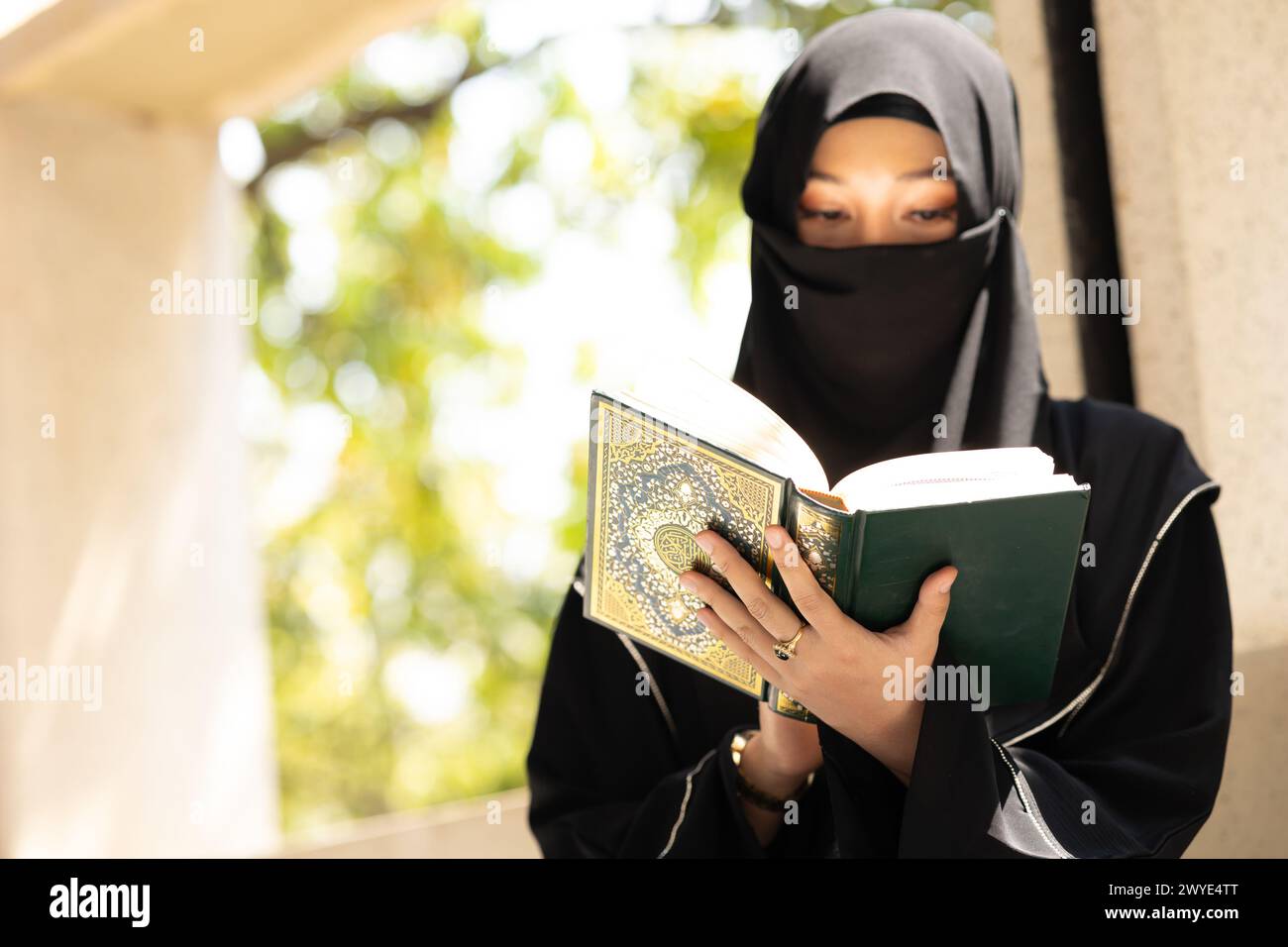 Muslim niqab woman read and learning the Quran and faith The Holy Al Quran book. Arab saudi black chador lady. Stock Photo