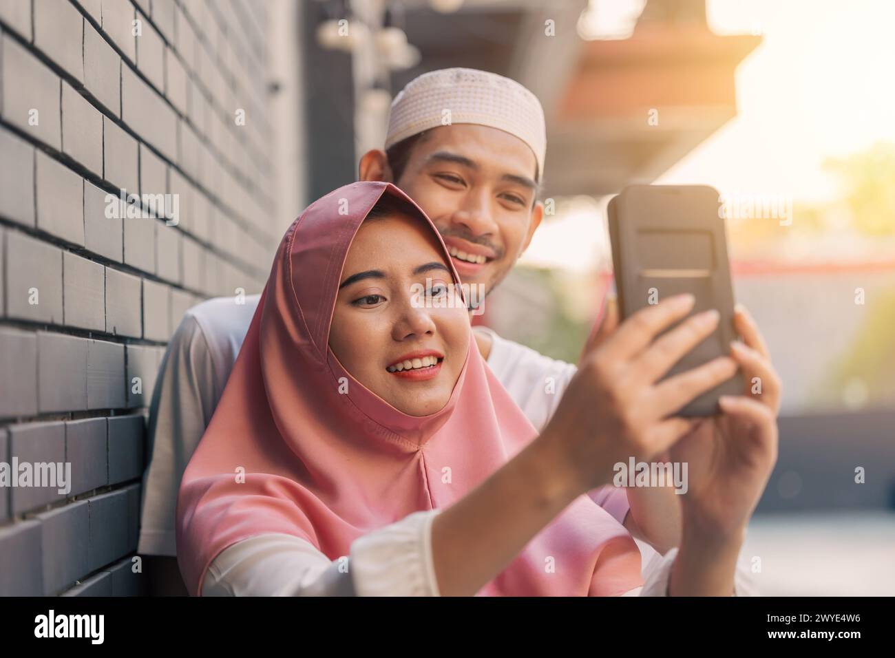 muslim people teen happy play smartphone relax enjoy together. islamic using cell phone outdoors Stock Photo