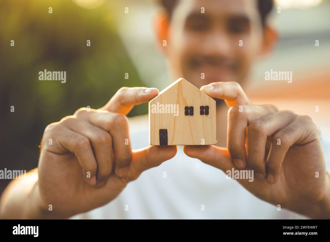people hand holding miniature wooden house model for banking housing