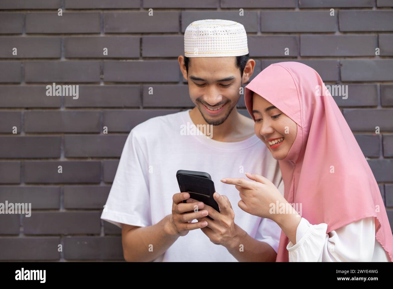 muslim people teen happy play smartphone relax enjoy together. islamic using cell phone outdoors Stock Photo