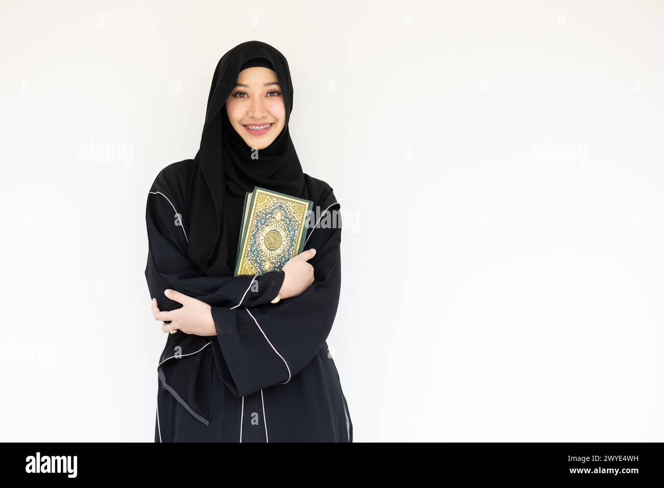 Portrait happy Saudi muslim niqab arab woman black chador with The Holy Al Quran book isolated on white. book cover arabic calligraphy translated to A Stock Photo