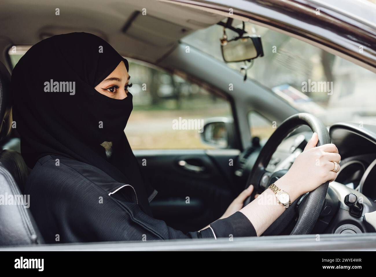 Saudi muslim women driving a car. Modern arab lady drive automotive vehicle. Stock Photo