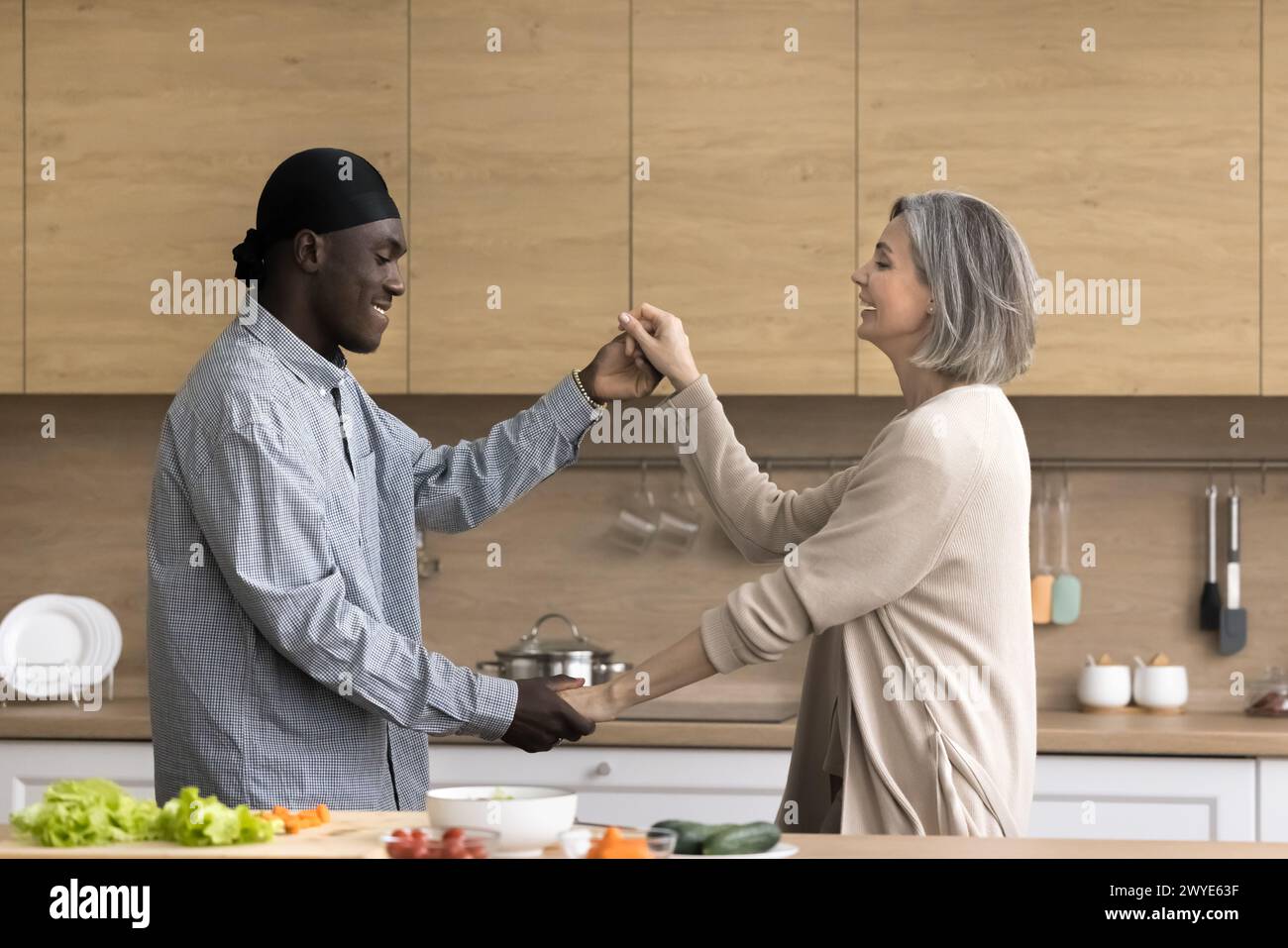 Happy multiethnic couple dancing in the kitchen Stock Photo