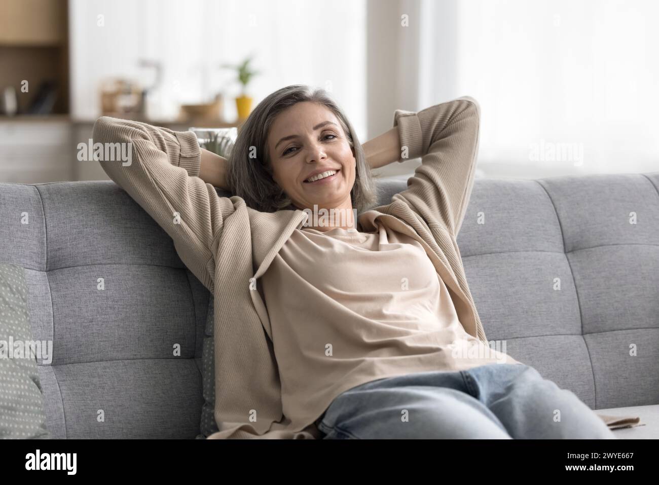 Happy mature woman relaxing on sofa and looking at camera Stock Photo ...