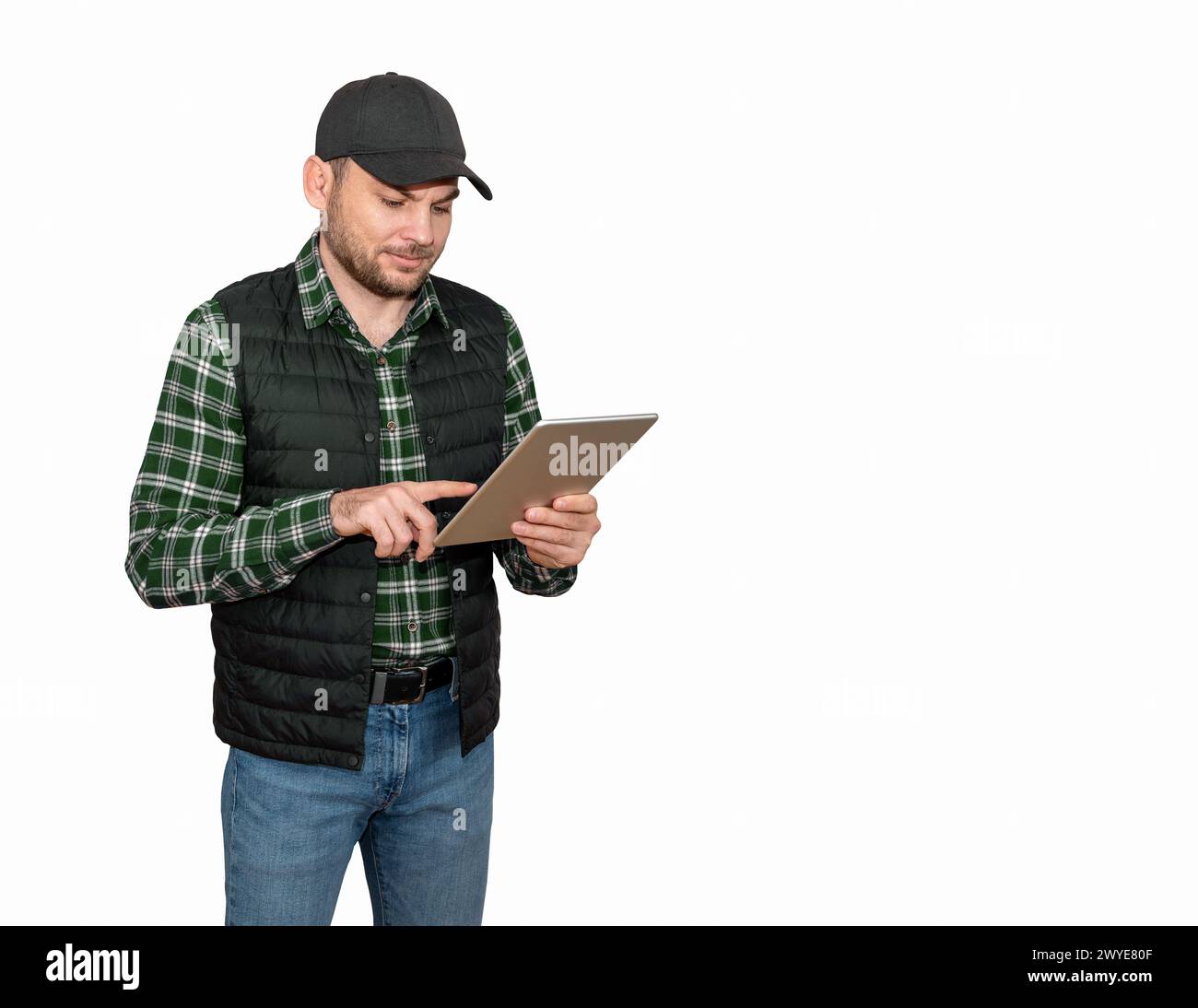 Isolated foreman or farmer wearing casual outfit and black cup using digital tablet and smiling. Stock Photo