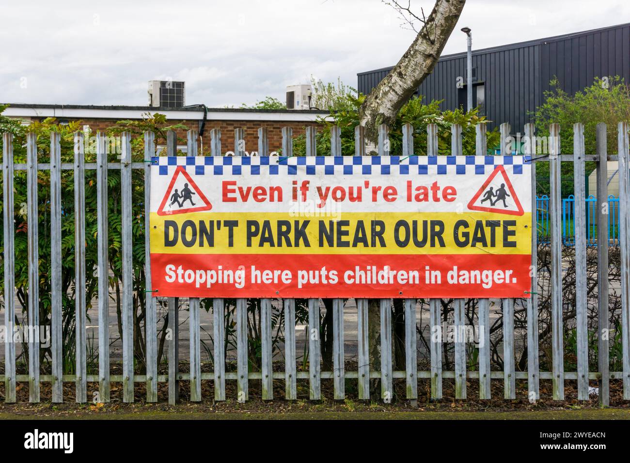 A banner outside a primary school entrance reads: Even if you're late don't park near our gate. Stock Photo