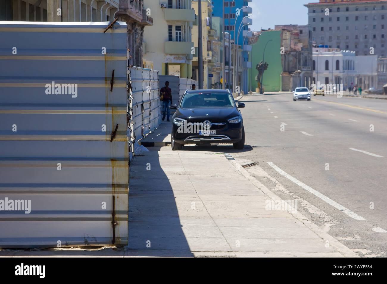 Construction fence and a Mercedes Benz car parked in the sidewalk, Havana, Cuba Stock Photo
