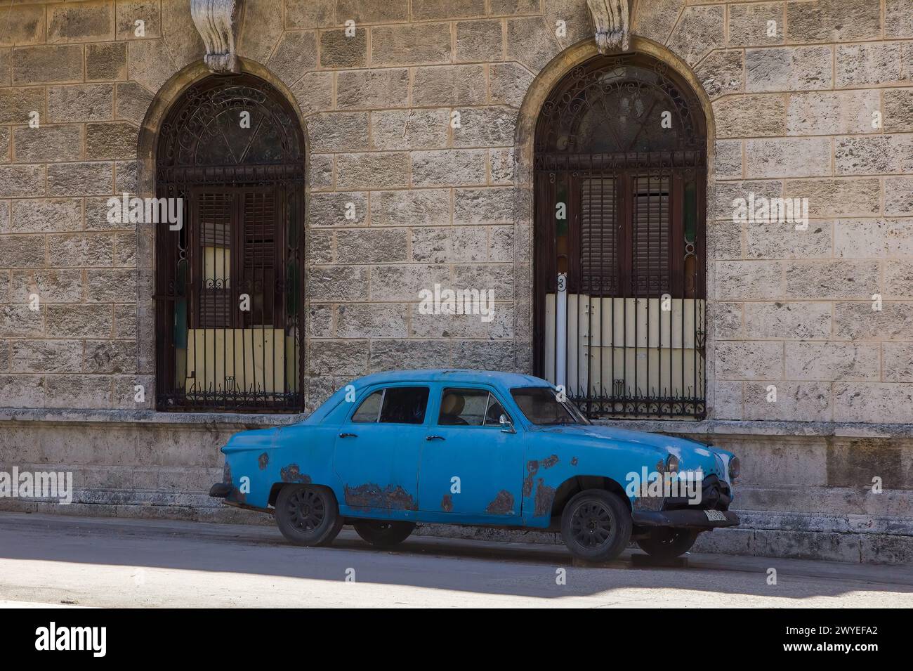 Shabby old car parked by a stone wall in Havana, Cuba Stock Photo