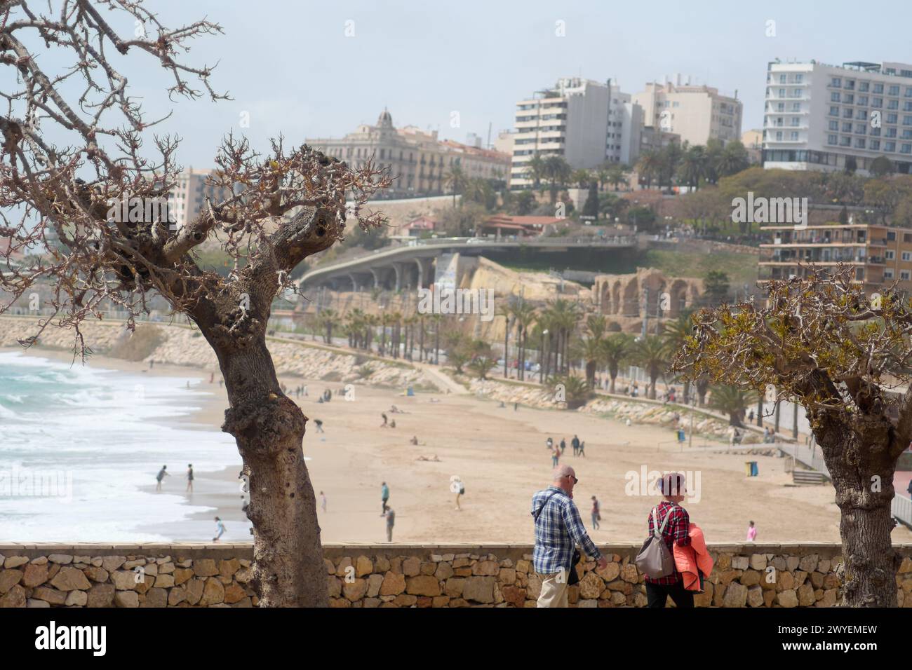 Tarragona, Spain - April 6, 2024 The image shows the coastal beauty of Tarragona with a lively beach, historic and modern architecture, and people enj Stock Photo