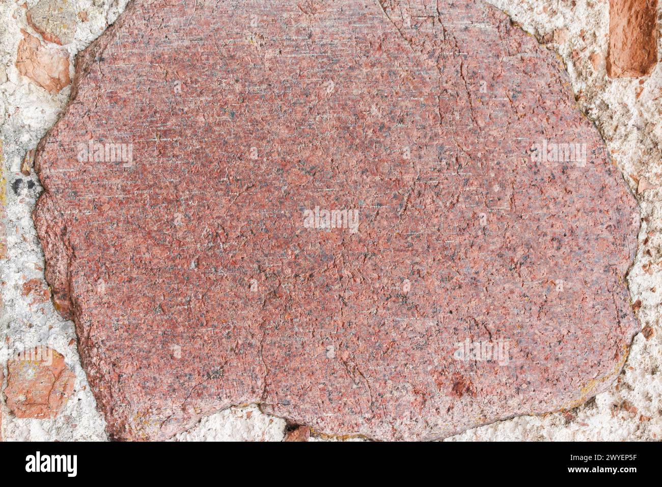 A large stone built into a brick wall. Stock Photo
