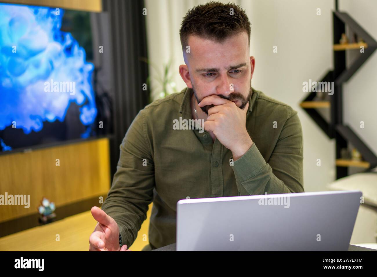 A young bearded Albanian man working on his notebook from home. Stock Photo