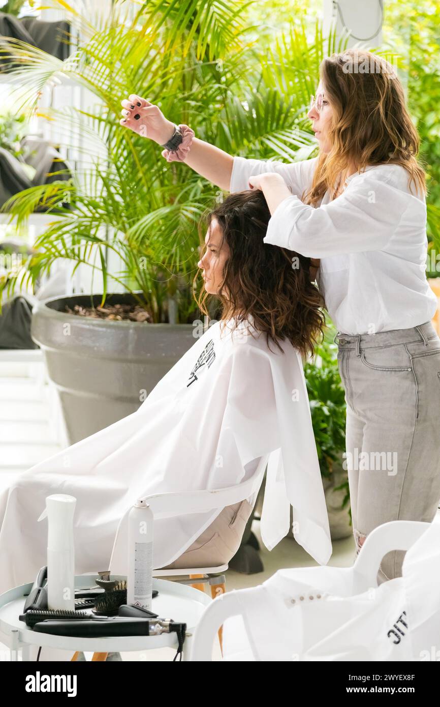 Cape Town, South Africa - November 15, 2022: Professional stylist working on young female model in hair salon Stock Photo
