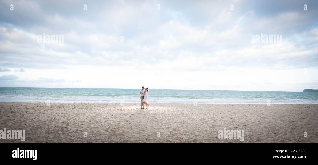 Couple Embracing on a Serene Beach: A Moment of Love and Connection Captured on Pristine Sands Under a Vast Sky Stock Photo