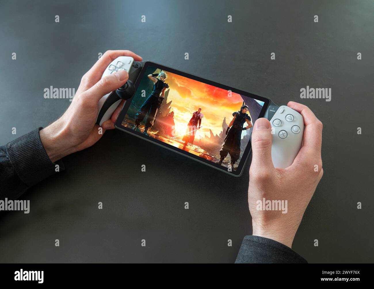 PlayStation Portal Remote Player - handheld gaming accessory for the PlayStation 5 by Sony. Close up of hands of a person playing Final Fantasy 7 Rebi Stock Photo