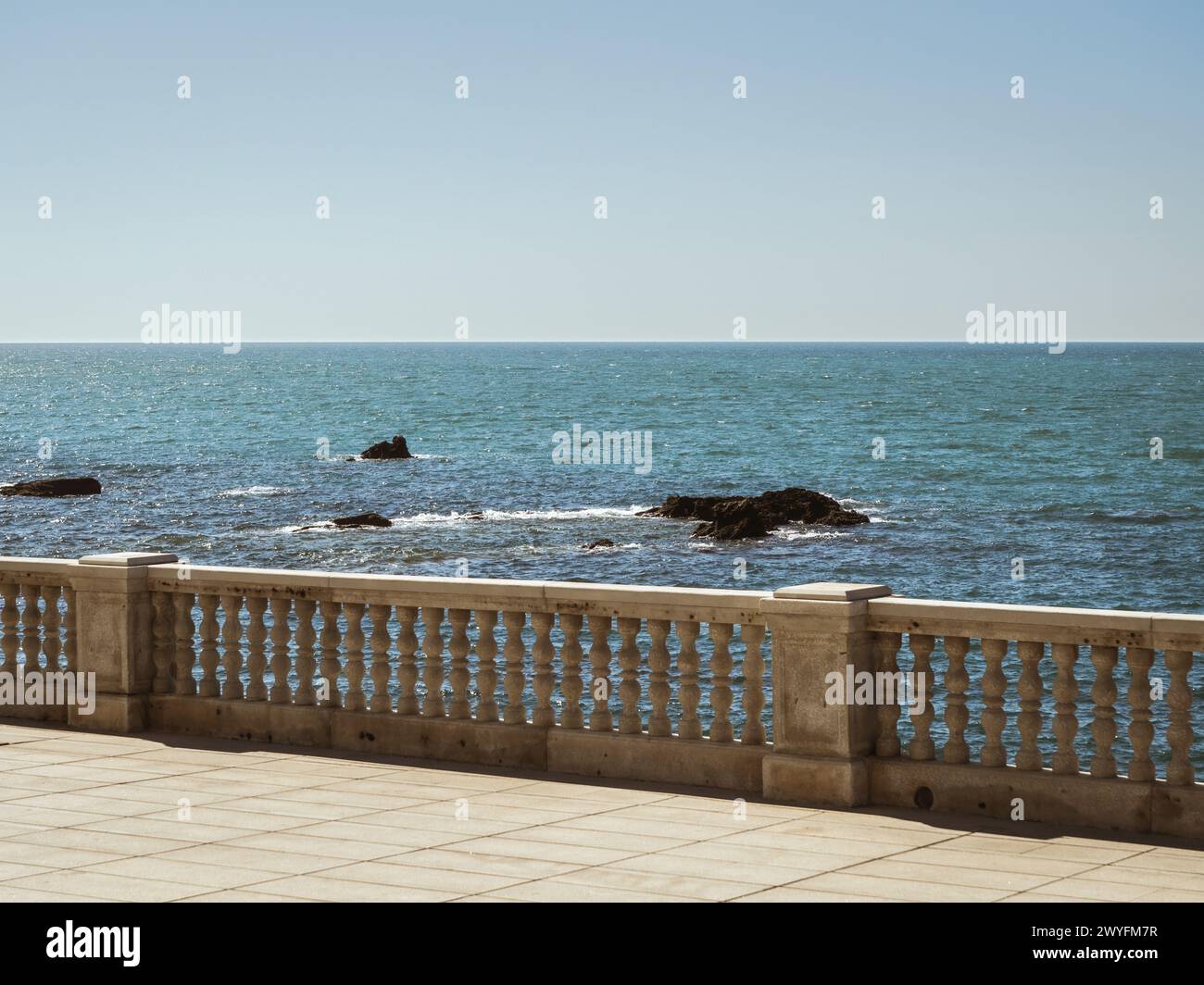View of the seaside beach promenade of Cadiz with rock formations in the water during a summer vacation, sea view, blue horizon, sunshine Stock Photo