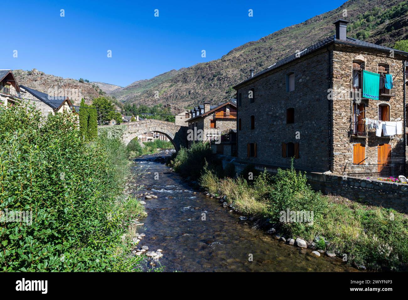 Typical houses and the Romanesque bridge over the Noguera Pallaresa river of the rustic village of Esterri Aneu, Lleida, Catalonia, Spain Stock Photo