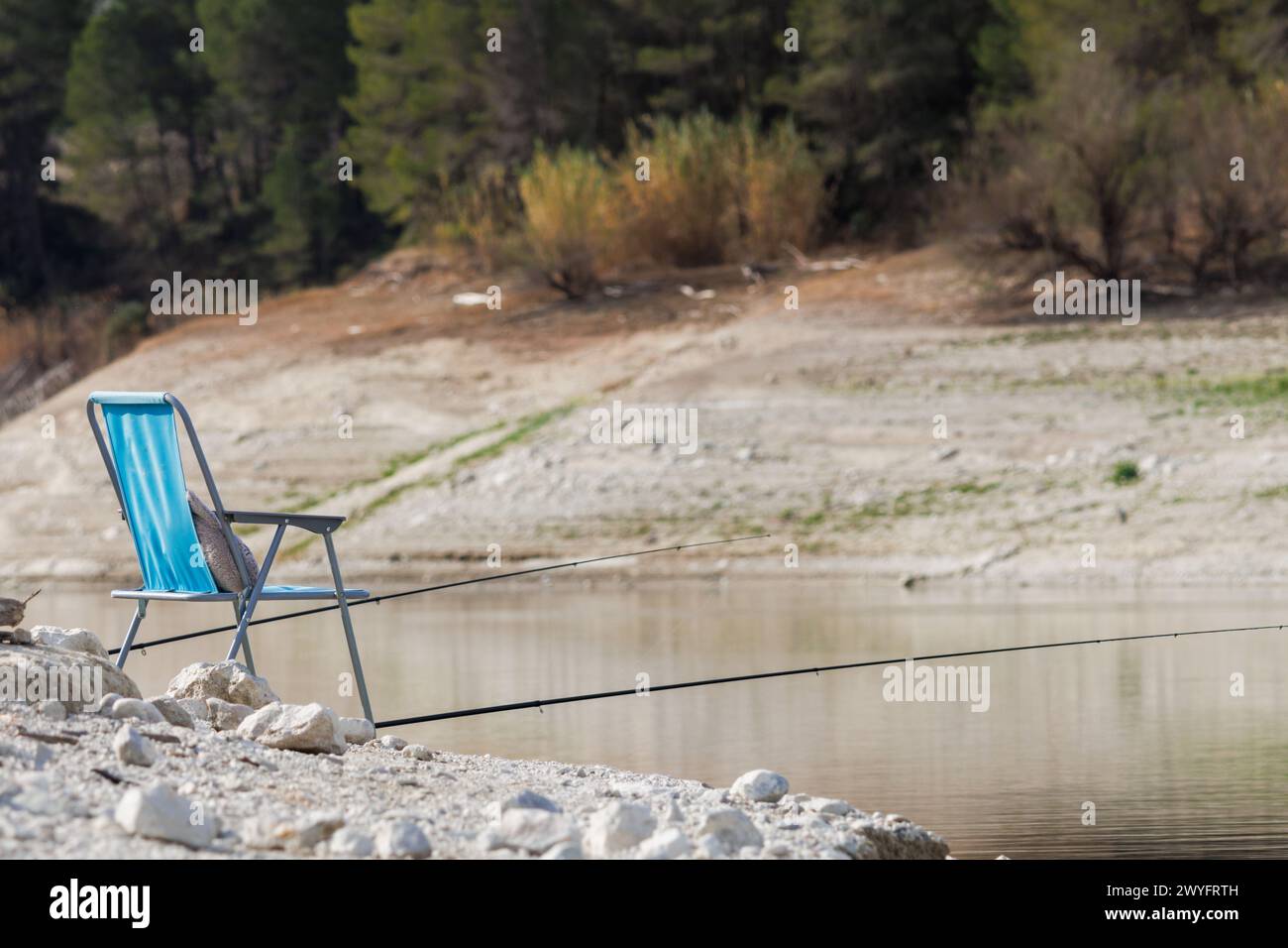 Fishing rods and chair prepared for a long day of fishing in the Beniarres reservoir, Spain Stock Photo