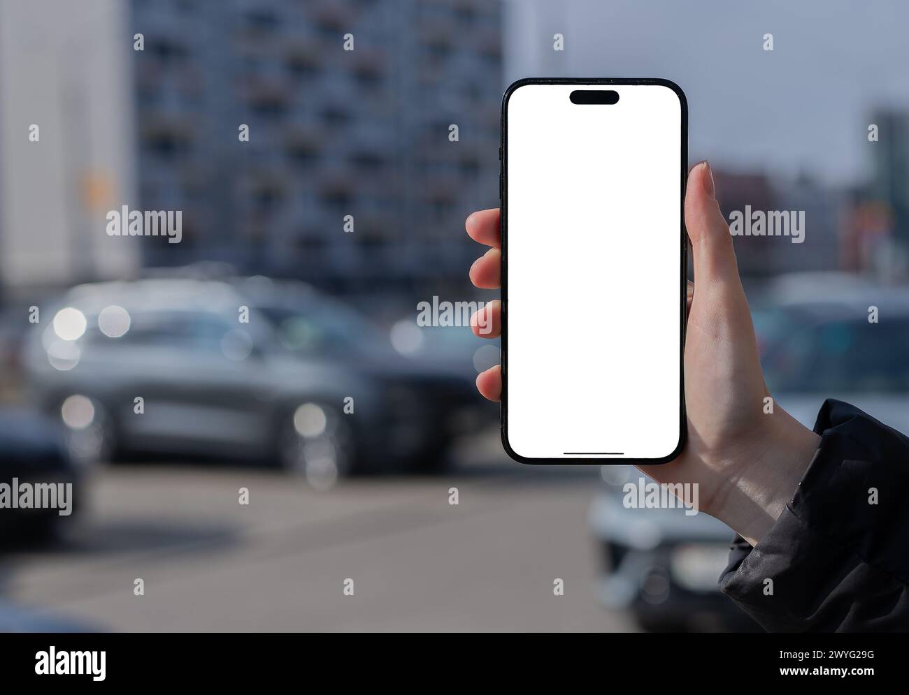 Berlin Germany January 21 2024 Hand holding mobile phone screen mock up, iphone mockup, city background, car, building. Stock Photo