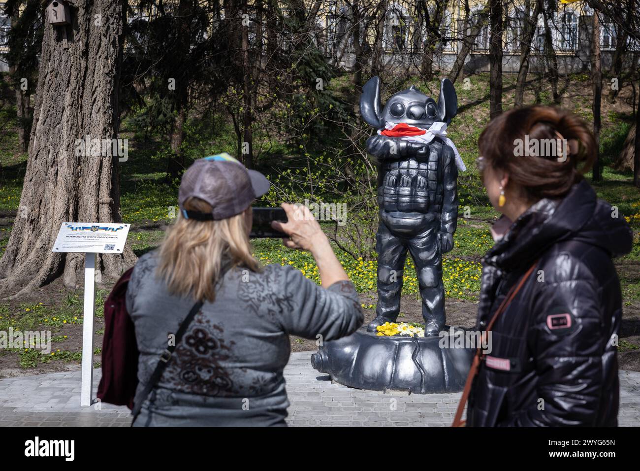 April 5, 2024, Kyiv, Ukraine: People take a pictures of a monument depicting the cartoon character Stitch from the cartoon 'Lilo and Stitch' in military uniform, erected in honor of the Ukrainian sniper Ihor Voevodin with nickname Stitch, who died in battles with the Russian army, in central Kyiv. Ukrainian student Ihor Voevodin volunteered for the front after the Russian invasion and served as a sniper in Azov regiment. Ihor Voevodin was killed in August 2023 on a combat mission in Luhansk region, Ukraine. (Credit Image: © Oleksii Chumachenko/SOPA Images via ZUMA Press Wire) EDITORIAL USAGE O Stock Photo