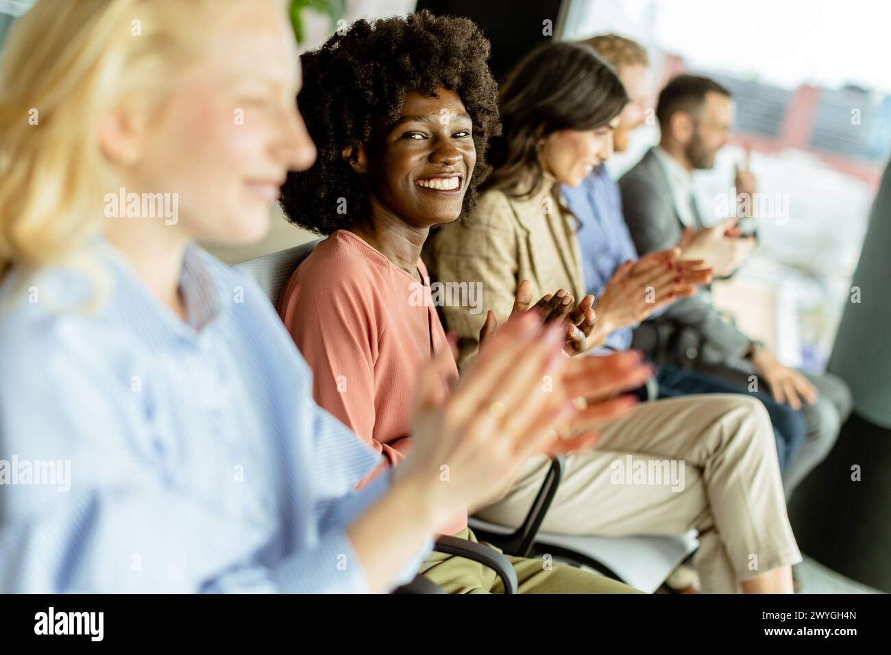 Smiling woman leads a round of applause with peers, sharing a moment of joy Stock Photo