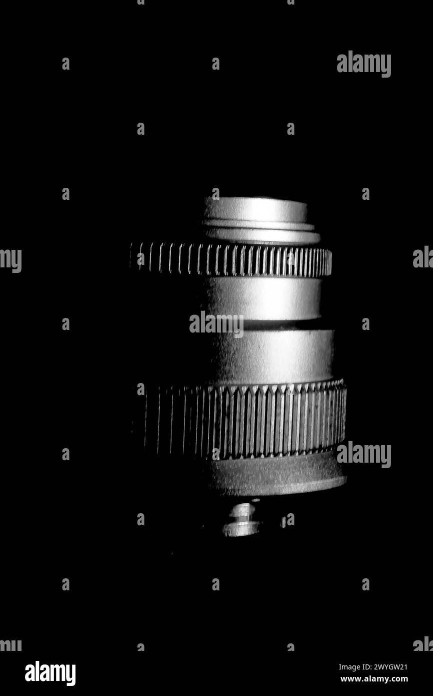 The image is a black and white close-up of a camera lens. The lens has several curved glass elements and a metal housing. Stock Photo