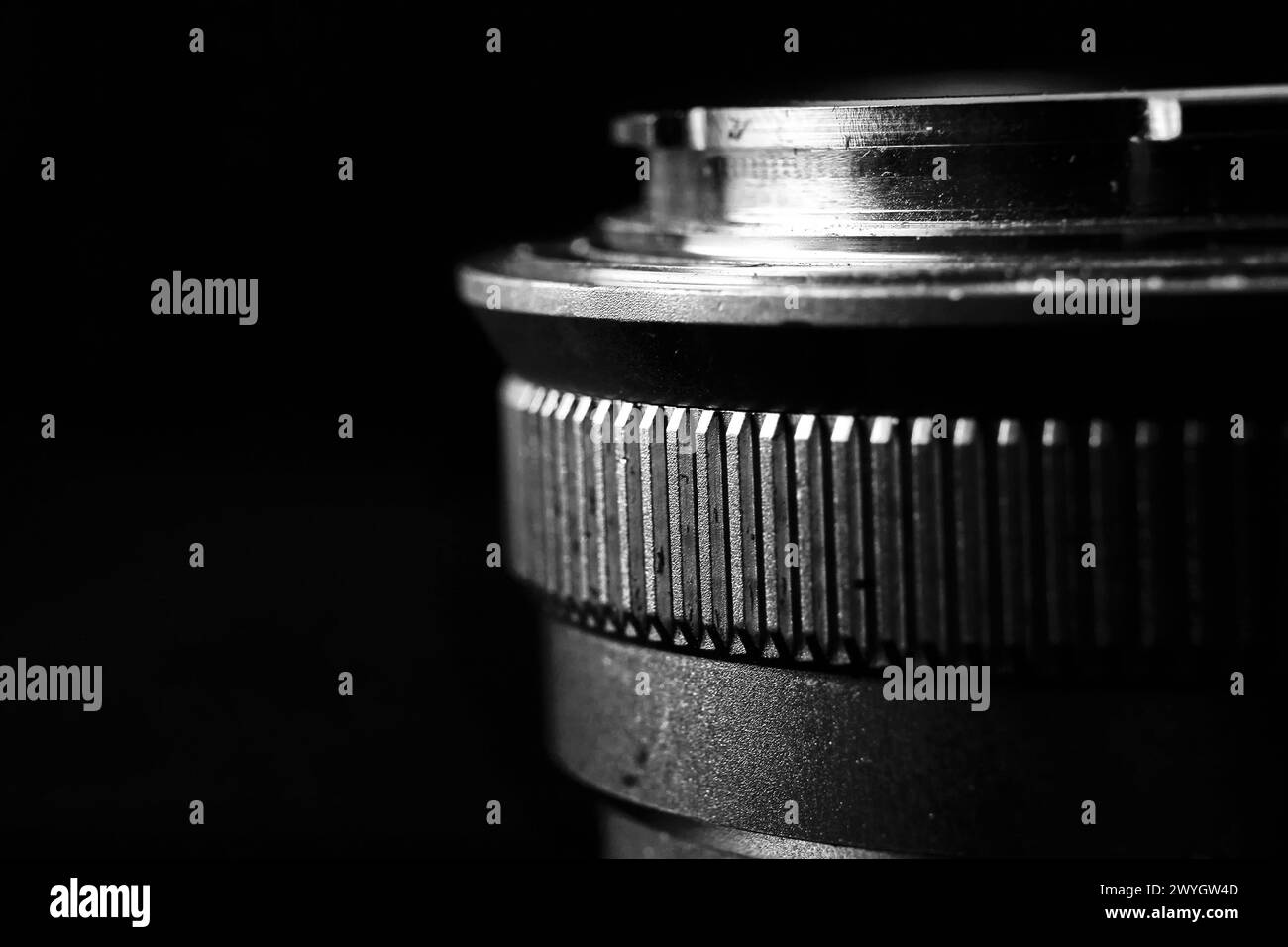 The image is a black and white close-up of a camera lens. The lens has several curved glass elements and a metal housing. Stock Photo