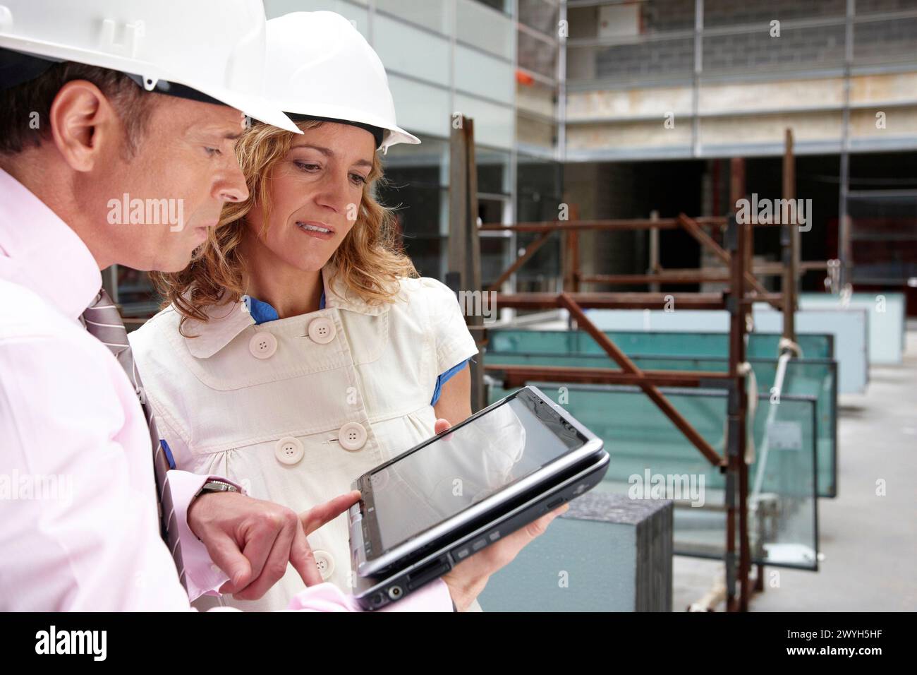 Architect and client with tablet PC in construction site. Stock Photo