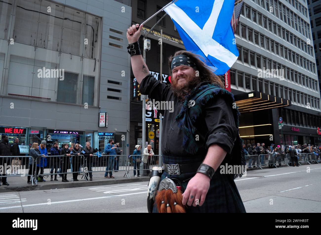 New York, United States. 06th Apr, 2024. A parade participant marches while waving the Scottish flag at the 26th annual New York City Tartan Day Parade on Sixth Avenue. The annual parade commemorating Scottish culture, draws bagpipers, Highland dancers, Scottish-American organizations and revelers to midtown Manhattan, New York City. In 1998, the United States Senate established April 6 as National Tartan Day 'to recognize the outstanding achievements and contributions made by Scottish Americans to the US.' (Photo by Jimin Kim/SOPA Images/Sipa USA) Credit: Sipa USA/Alamy Live News Stock Photo