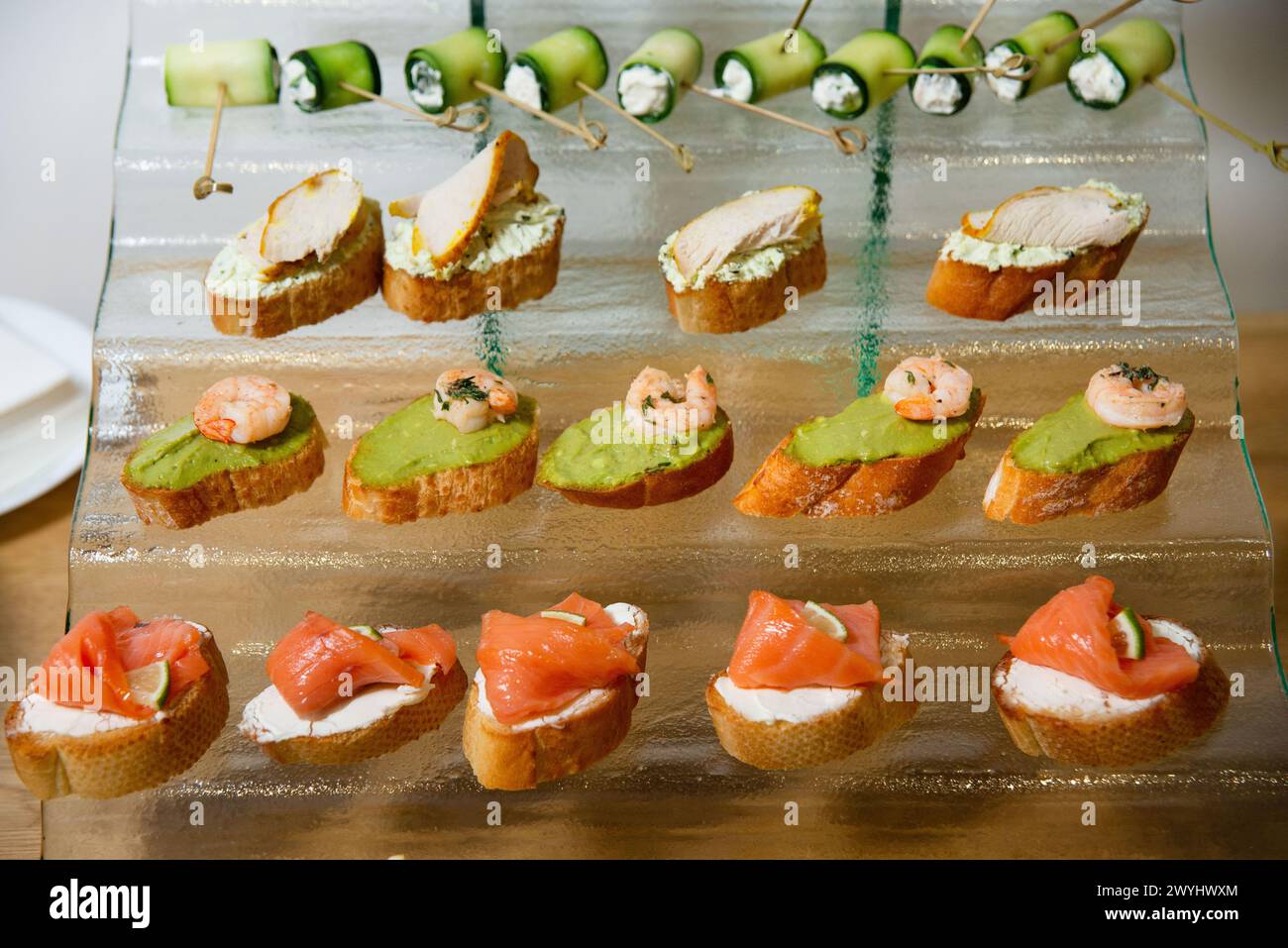 Elegant selection of canapés topped with smoked salmon, fresh avocado, and shrimp, perfect for high-end catering events or cocktail parties. Stock Photo