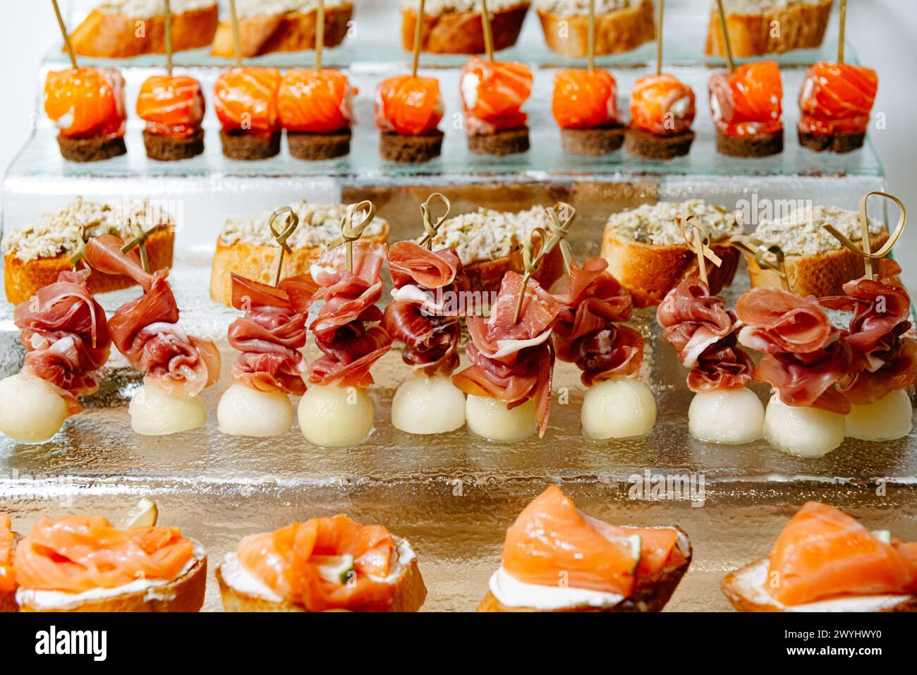 A luxurious selection of canapés featuring smoked salmon on toast, prosciutto with melon, and tuna spread, perfect for high-end catering and events. Stock Photo