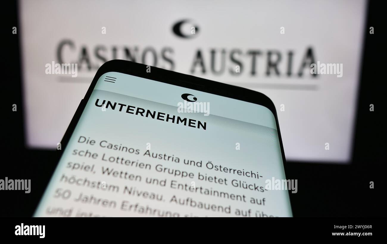 Smartphone with website of Austrian gambling company Casinos Austria AG in front of business logo. Focus on top-left of phone display. Stock Photo
