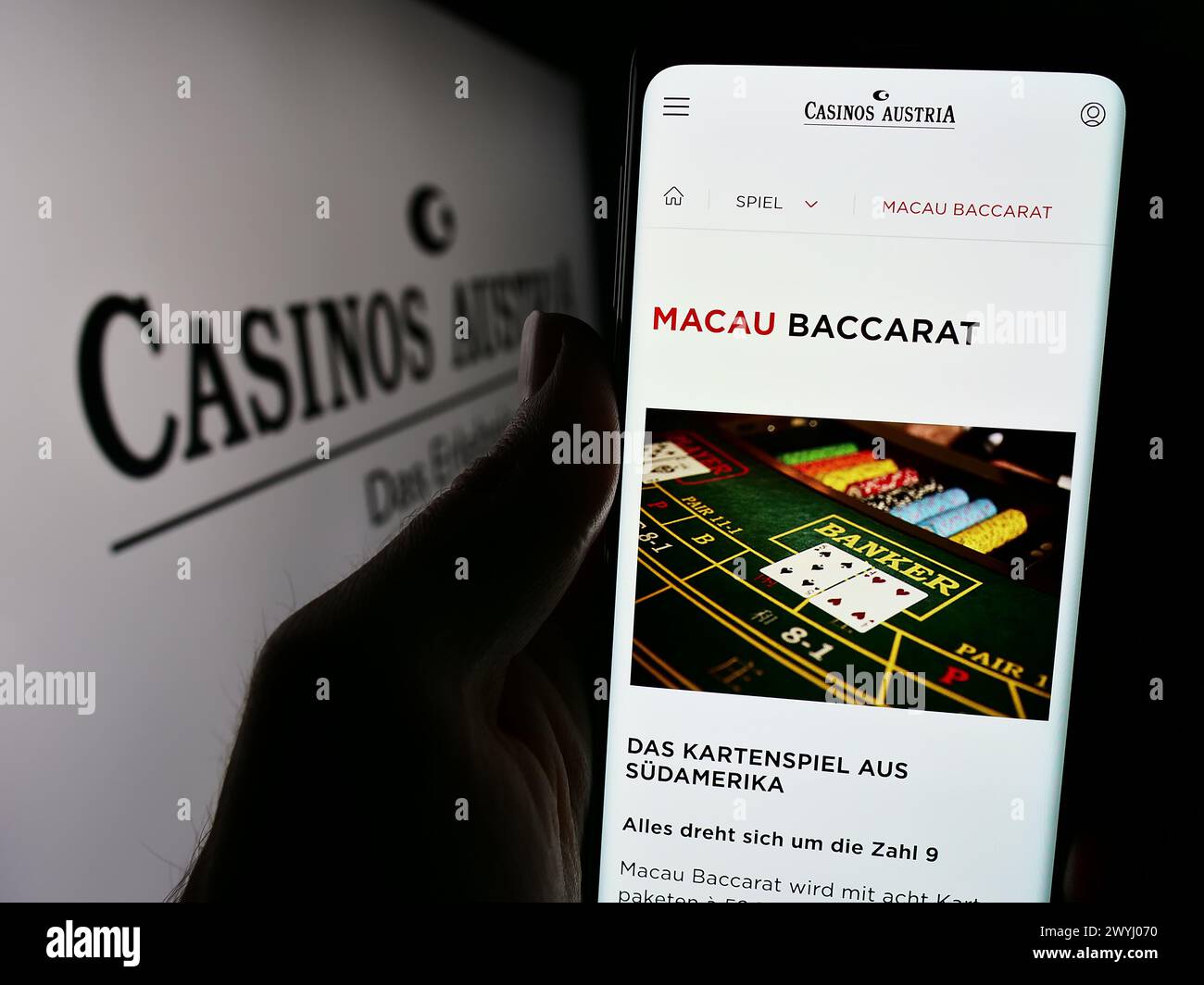 Person holding cellphone with webpage of Austrian gambling company Casinos Austria AG in front of logo. Focus on center of phone display. Stock Photo