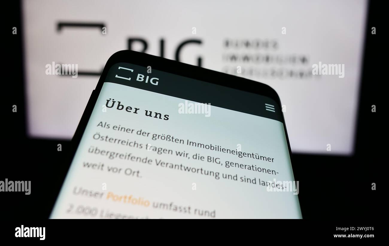 Mobile phone with website of company Bundesimmobiliengesellschaft m.b.H. (BIG) in front of business logo. Focus on top-left of phone display. Stock Photo
