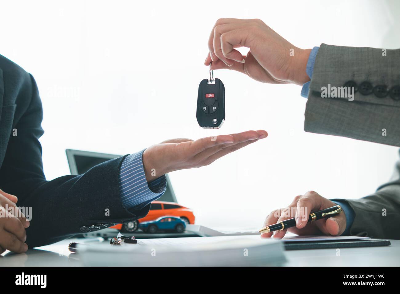 car dealer is handing over car keys to customer after sales contract and installment contract have been signed. Concept of handing over car keys to cu Stock Photo