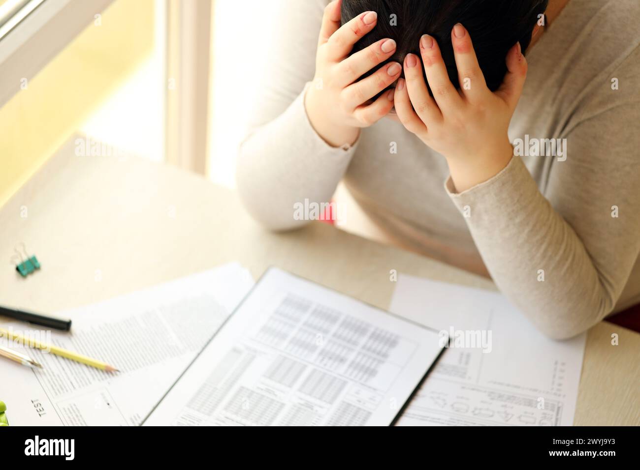Sad female student testing in exercise and fill exam paper sheet with ...