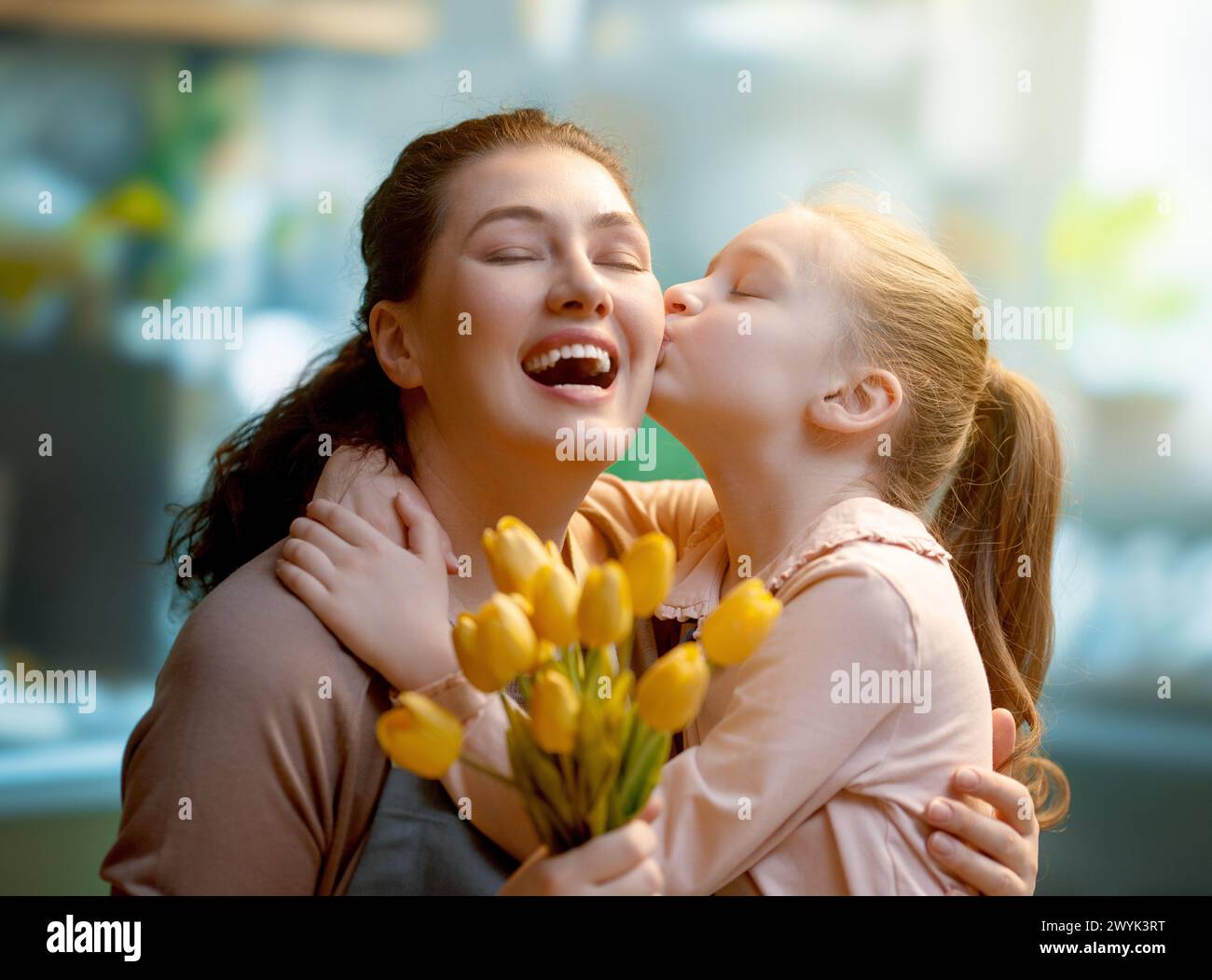Happy mother's day. Child daughter is congratulating mom and giving her flowers. Mum and girl smiling and hugging. Family holiday and togetherness. Stock Photo