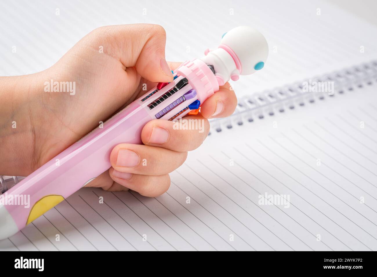 Little girl chooses color from a pen that can write in different colors ...